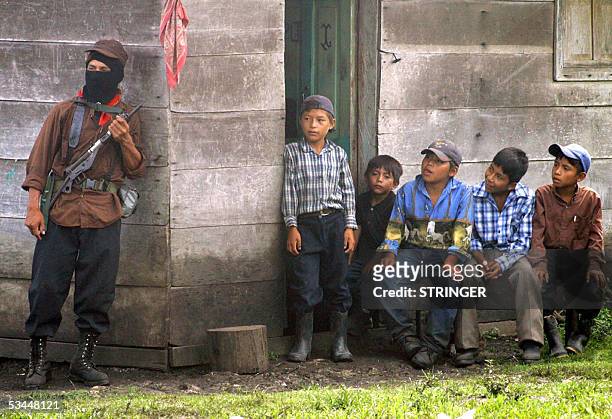 Mexican indigenous children look at a Zapatista Army of National Liberation member who guards the house where Subcomandante Marcos, leader of the...