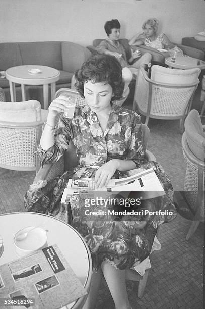 Israeli actress Haya Harareet sitting in a café and reading a magazine during the 19th Venice International Film Festival. Venice, August 1958