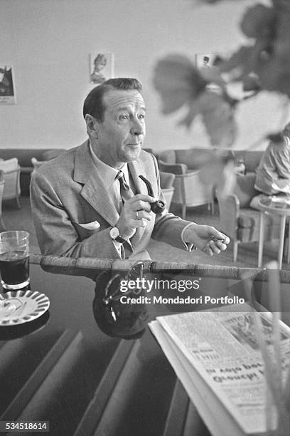 Belgian writer Georges Simenon sitting at the counter with his inevitable pipe at the 19th Venice International Film Festival. Venice, August 1958