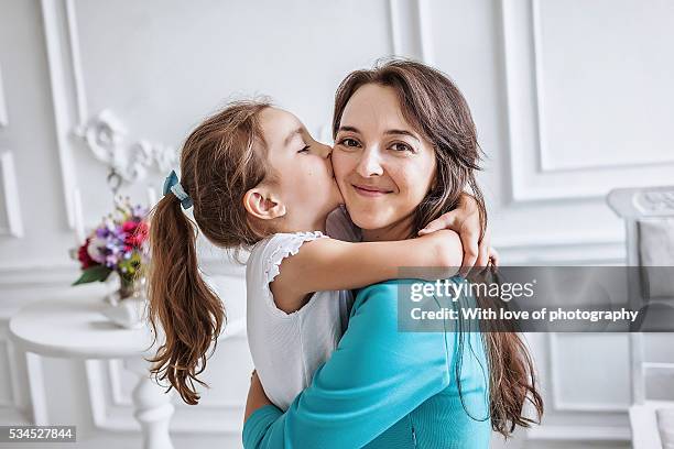 little girl about 10 years old embracing and kissing her smiling beautiful mother both looking at camera, family - mama kind kuscheln stock-fotos und bilder