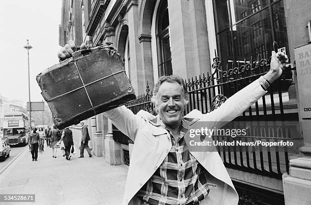 English actor and campaigner, Brian Rix pictured holding an ancient briefcase outside the Whitehall Theatre in London on 3rd August 1976. Rix is...