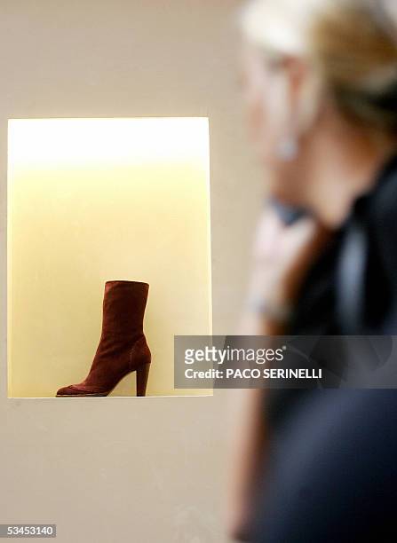 Una mujer observa una vidriera de una zapateria el 23 de agosto de 2005 en Roma. La prestigiosa industria del calzado italiana se ve confrontada hoy...
