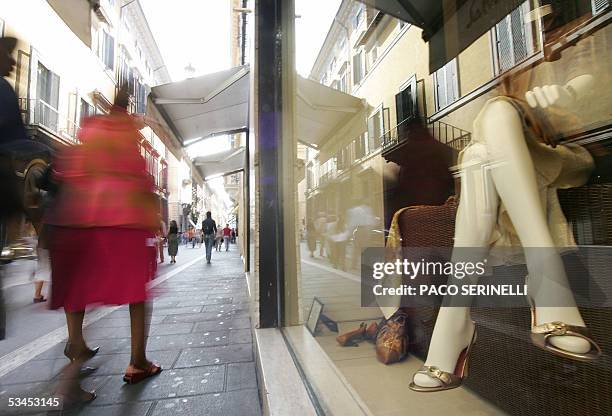 Una mujer pasa junto a una vidriera de una zapateria el 23 de agosto de 2005 en Roma. La prestigiosa industria del calzado italiana se ve confrontada...