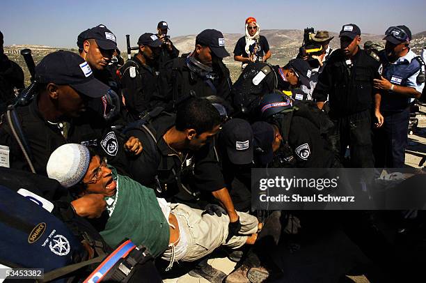 Israeli police carry away a right-wing settler activist during the evacuation on August 23, 2005 of Sanur settlement in the West Bank. Israel...