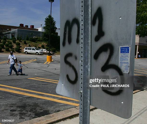 Unidentified man walks with a young boy thru a grocery store parking lot near a typical traffic sign 23 August 2005 with the back of it spray painted...