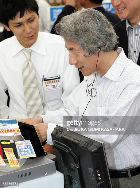 Japanese Prime Minister Junichiro Koizumi tries an HDD music player during his inspection tour to a shop in Tokyo's Akihabara electronics district,...