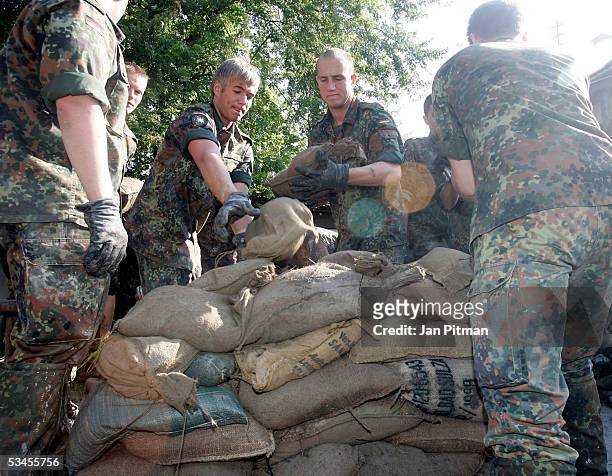 German soldiers remove sandbags from a flood barrier on August 24, 2005 in Eschenlohe, Germany. People in southern Bavaria are cleaning up the...
