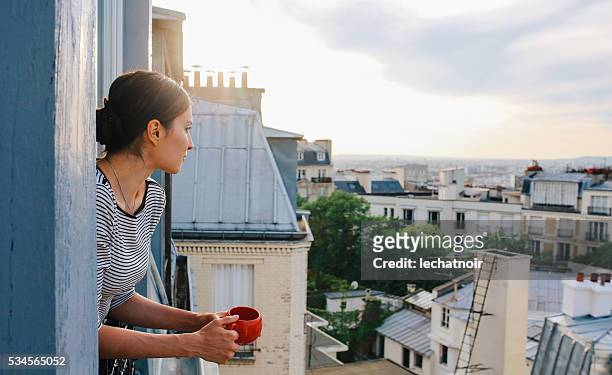 junge frau genießt die ansicht von einem pariser appartment - frankreich stock-fotos und bilder