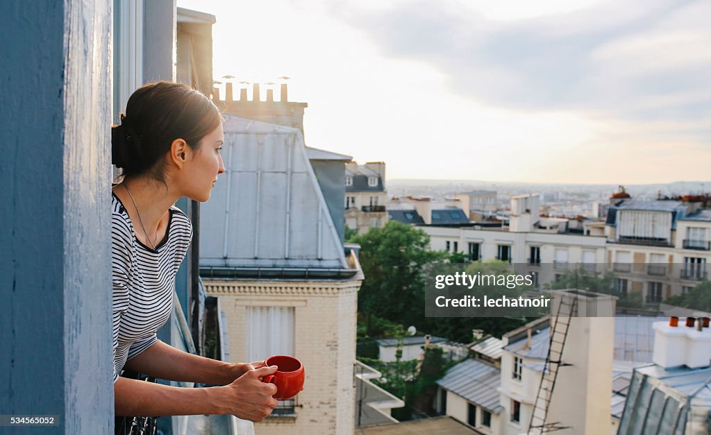 Young woman enjoying the view from a Parisian apartment