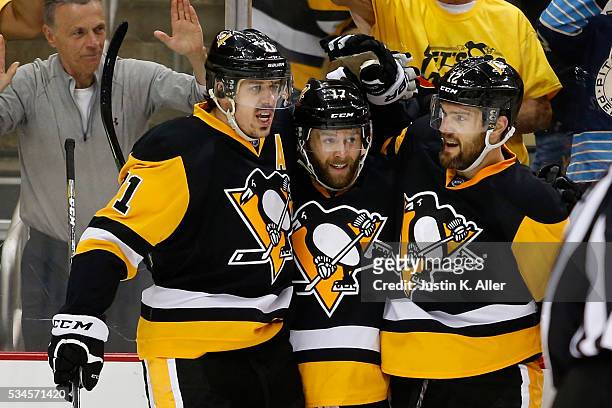 Bryan Rust of the Pittsburgh Penguins celebrates with his teammates Evgeni Malkin and Ben Lovejoy after scoring a goal against Andrei Vasilevskiy of...