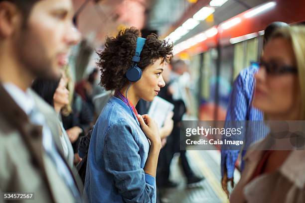 woman listening to headphones in train station - man woman train station stockfoto's en -beelden
