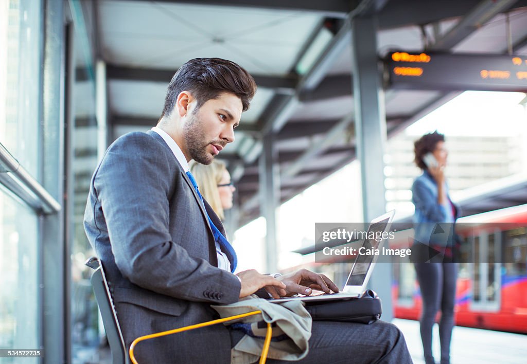 Businessman using laptop at train station