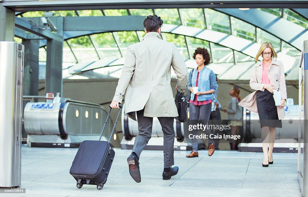 Businessman pulling luggage near escalators
