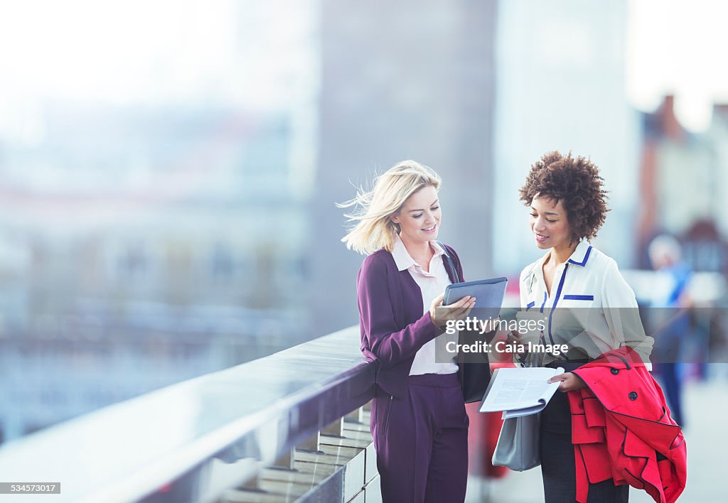 Businesswomen using digital tablet on urban bridge