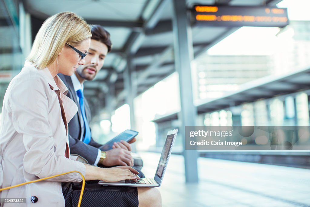 Business people using laptop at train station