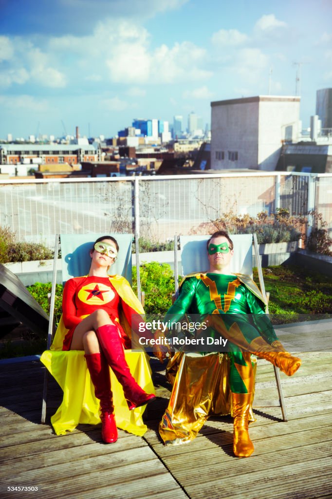 Superhero couple sitting on city rooftop