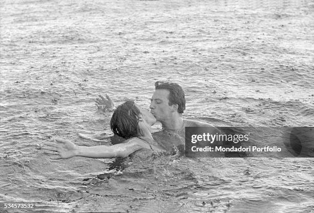 Italian actor Franco Interlenghi and his wife, Italian actress Antonella Lualdi , kissing in the sea under the rain during the XVIII Venice...