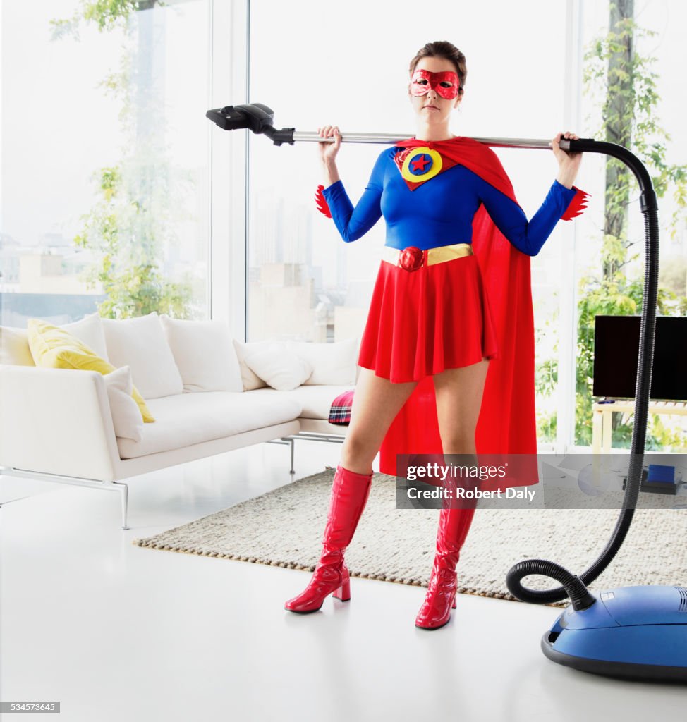 Superhero holding vacuum in living room