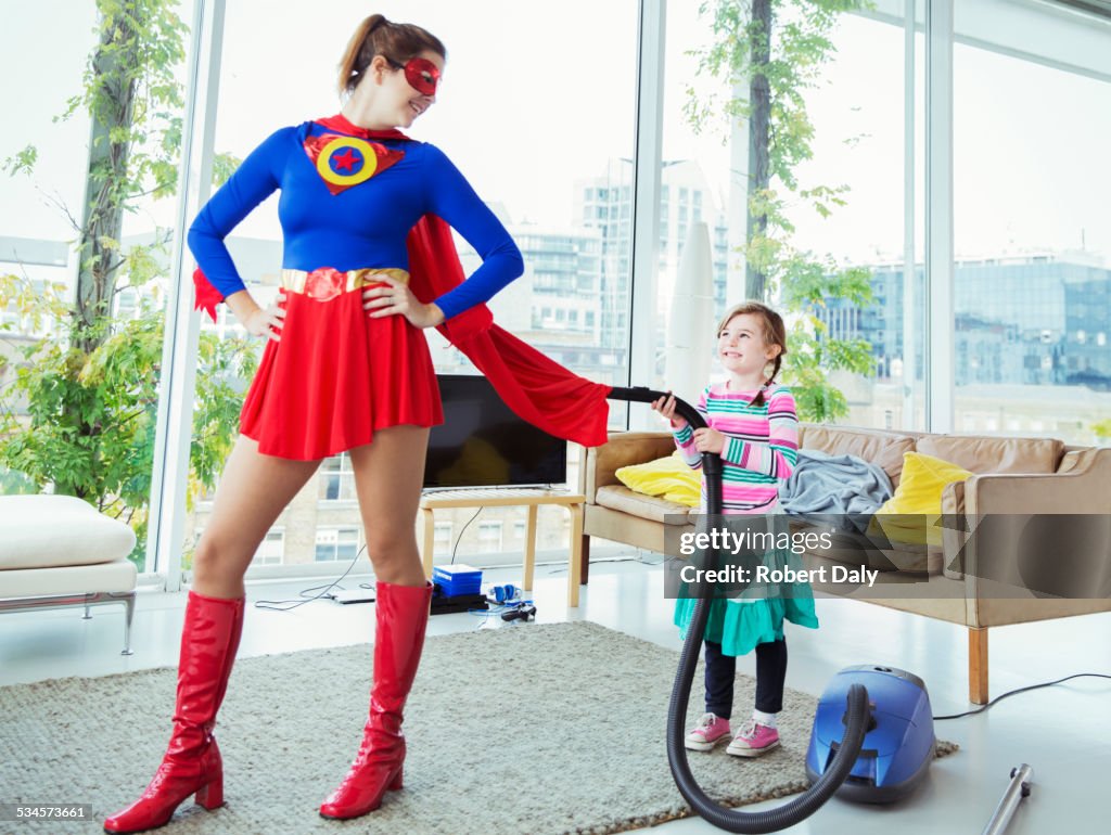 Daughter of superhero vacuuming her cape in living room