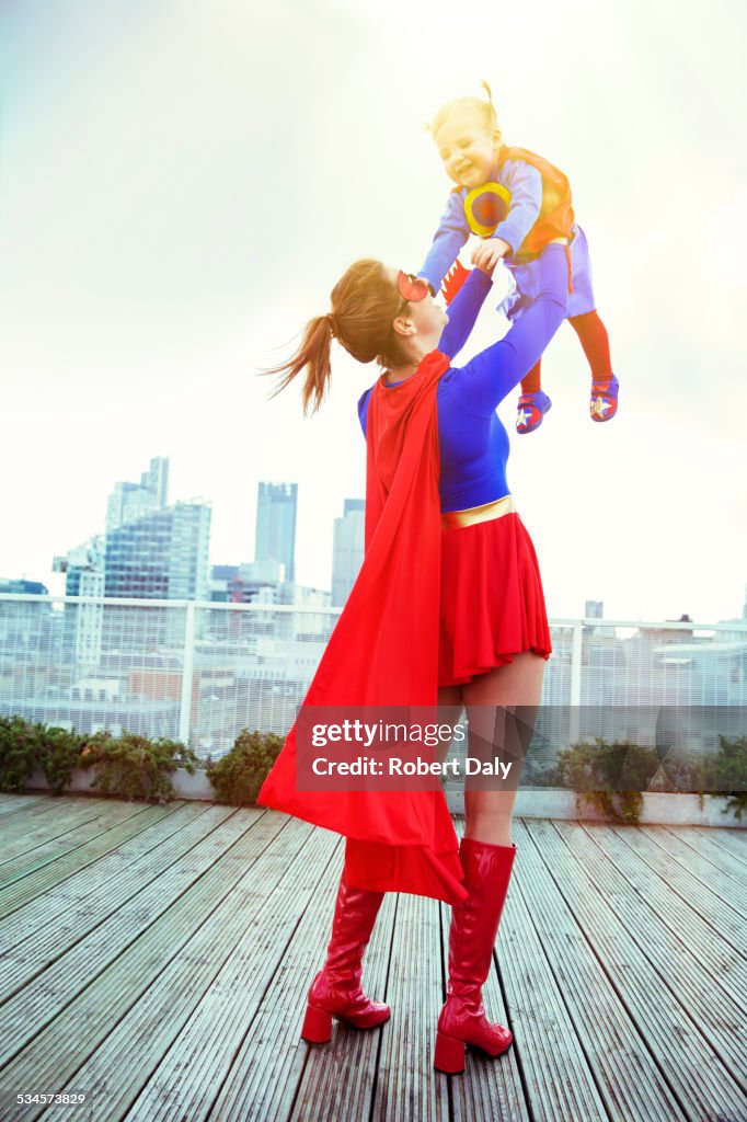 Madre superheroína jugando con su hija en la azotea de la ciudad
