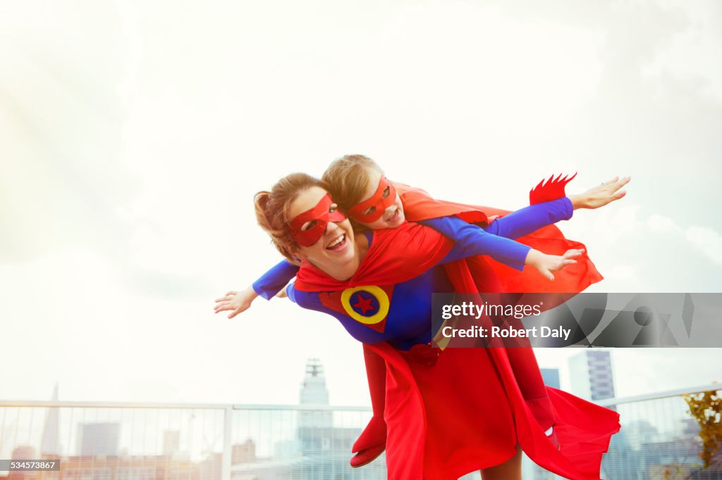 Superhero mother and daughter playing on city rooftop