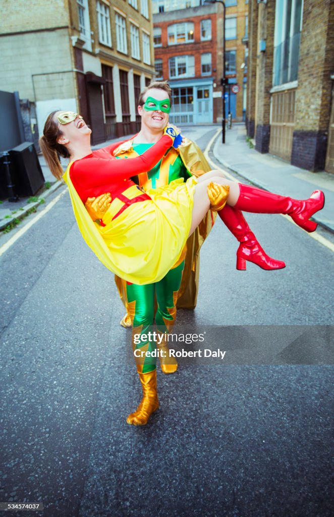 Superhero carrying wife on city street