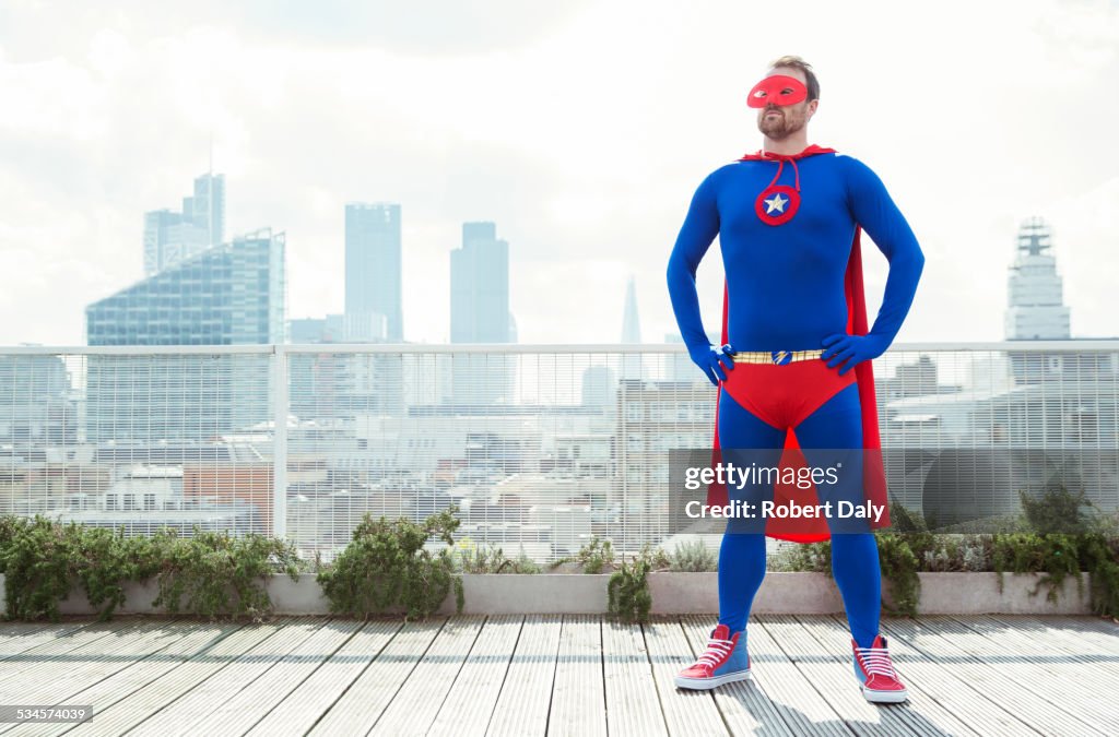 Superhero standing with hands on hips on city rooftop