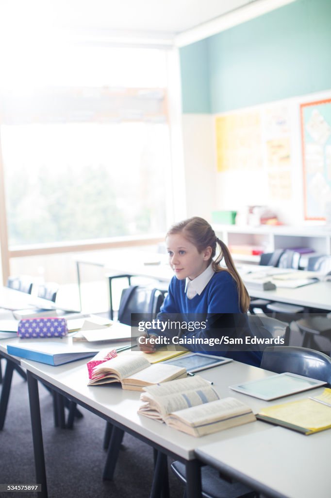 Female pupil sitting in classroom with tablet pc