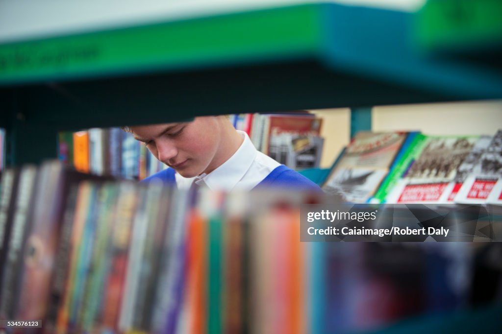 Student in library seen through book shelves