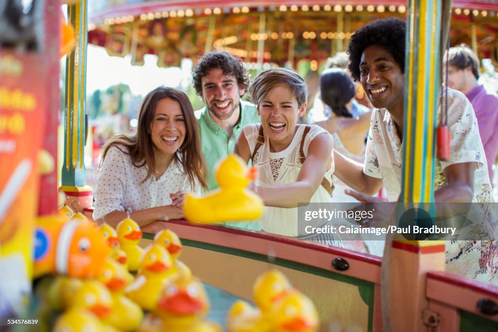 Group of friends having fun with fishing game in amusement park