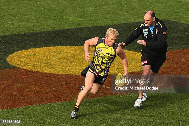 Steven Morris of the Tigers runs with the ball over the Aboriginal Flag painted on the ground during a Richmond Tigers AFL training session at ME...