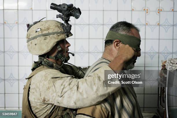 Marine Cpl. William Maher of Buffalo, New York serving with India Company 3rd Battalion 25th Marine Regiment blindfolds a prisoner following an early...
