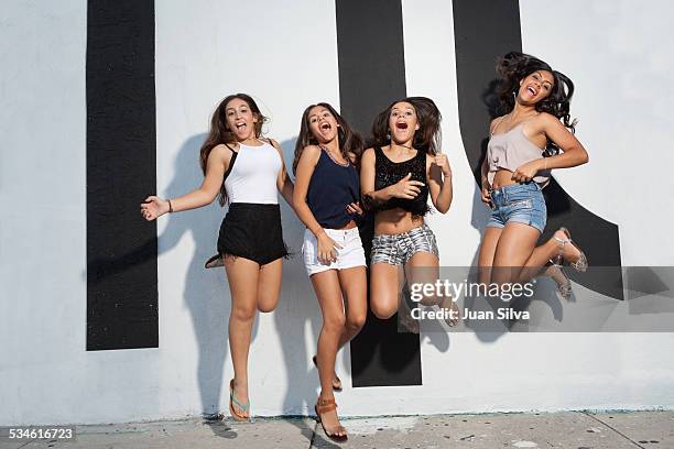 four teenage girls jumping on the street - hot pants stock-fotos und bilder