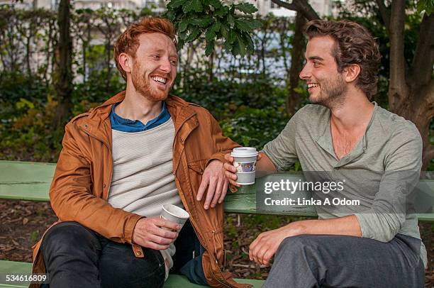 two attractive men drinking coffee in the park - bench park bildbanksfoton och bilder