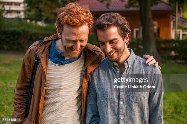 young gay couple walking and flirting in the park - two guys laughing stock pictures, royalty-free photos & images