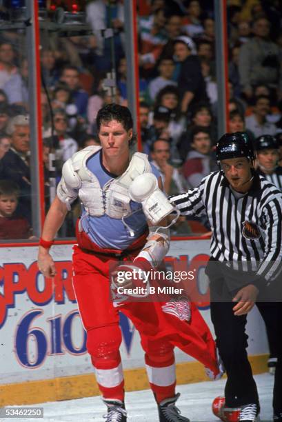 Canadian hockey player Bob Probert of the Detroit Red Wings, jersey on his hand, is escourted off the ice by an official after a fight at the...