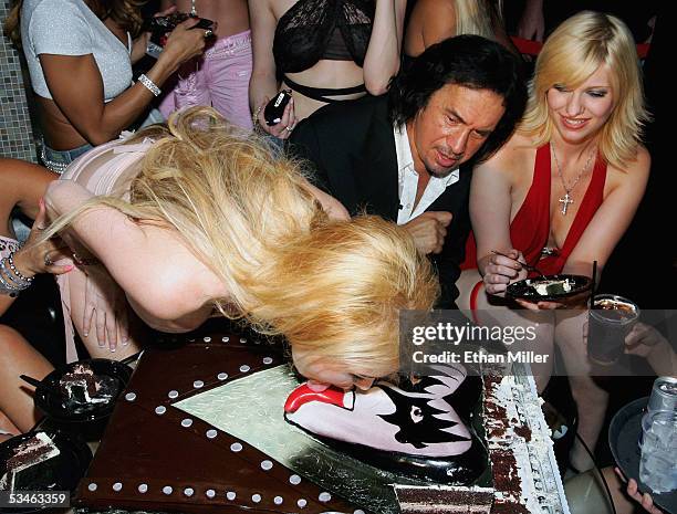Adult film actress Taylor Wane licks the tongue on Kiss singer/bassist Gene Simmons' birthday cake as he looks on during his birthday party at the...