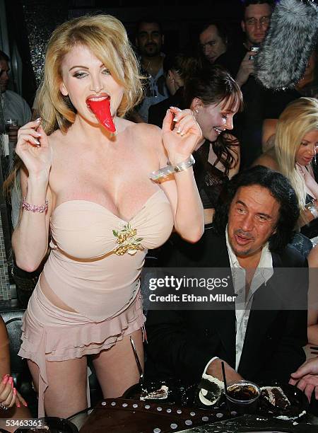 Adult film actress Taylor Wane plays with the tongue from Kiss singer/bassist Gene Simmons' birthday cake as he looks on during his birthday party at...