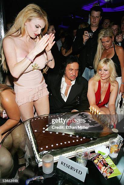 Kiss singer/bassist Gene Simmons checks out his birthday cake as adult film actress Taylor Wane looks on during his birthday party at the Palms...