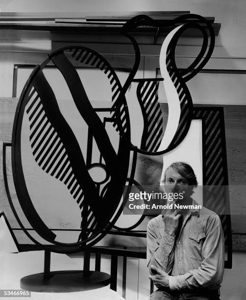 American artist Roy Lichtenstein poses next to one of his sculptures in his studio, Southampton, Long Island, New York, September 18, 1976.