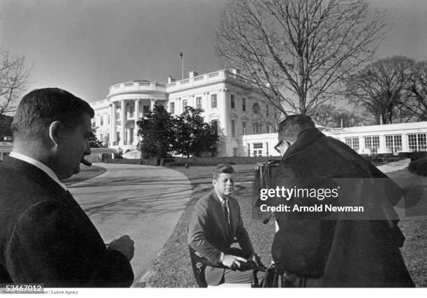 Photographer Arnold Newman photographs President John F Kennedy in front of the White House, as Press Secretary Pierre Salinger looks on, December...