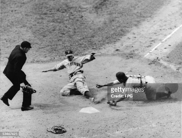 Pittsburgh Pirates centerfielder Vince DiMaggio slides past Brooklyn Dodgers catcher Bobby Bragan to score in the sixth inning of play during a game...