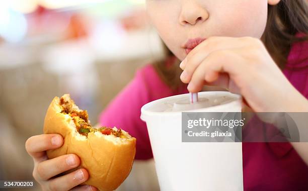 little girl eating burger and drinking soda. - unhealthy food stock pictures, royalty-free photos & images