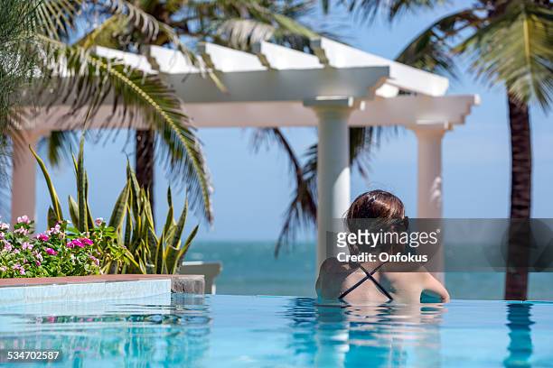 woman relaxing inside infinity pool at tropical resort - hot vietnamese women stock pictures, royalty-free photos & images