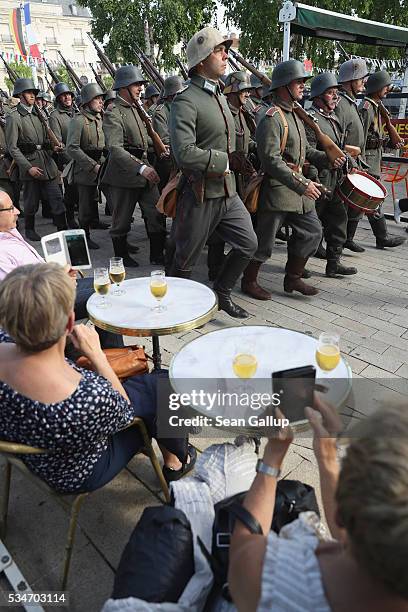 People at an outdoor cafe watch as history reenactors dressed as World War I German soldiers participate in a parade in the town center on May 27,...