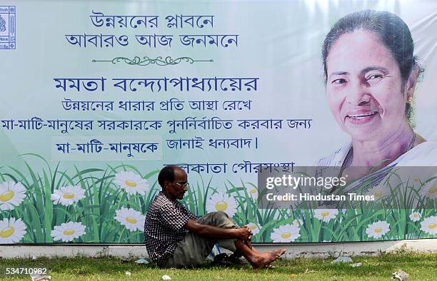 Man resting near huge banner of West Bengal Chief Minister Mamata Banerjee during her oath taking ceremony on May 27, 2016 in Kolkata, India. The...