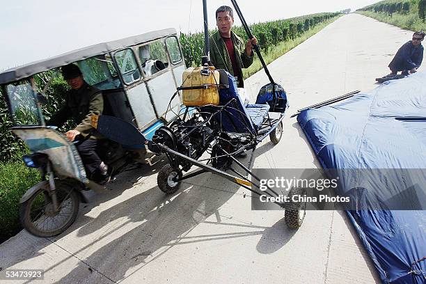 Chinese farmer Wang Qingliang installs the wings as he prepares to start his home-made plane at the Fenghuangtuo Village on August 27, 2005 in...
