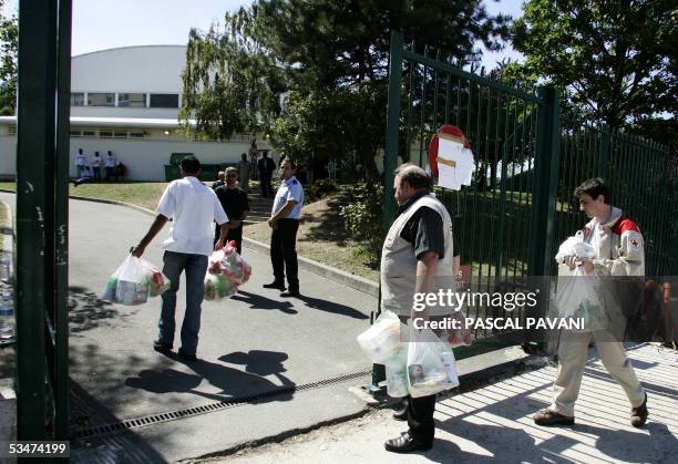 Red Cross members enter a gymnasium carrying food, 28 August 2005 in Paris, a day after seventeen people including fourteen children died and 30 were...