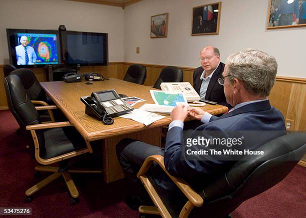 In this handout photo provided by the White House, U.S. President George W. Bush takes a map from Deputy Chief of Staff Joe Hagin during a video...