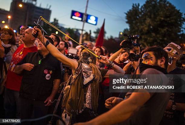 Hooded protestors use slingshots to throw colored paint balls on the Parliament building , during an anti-government protest in Skopje on May 27 in a...
